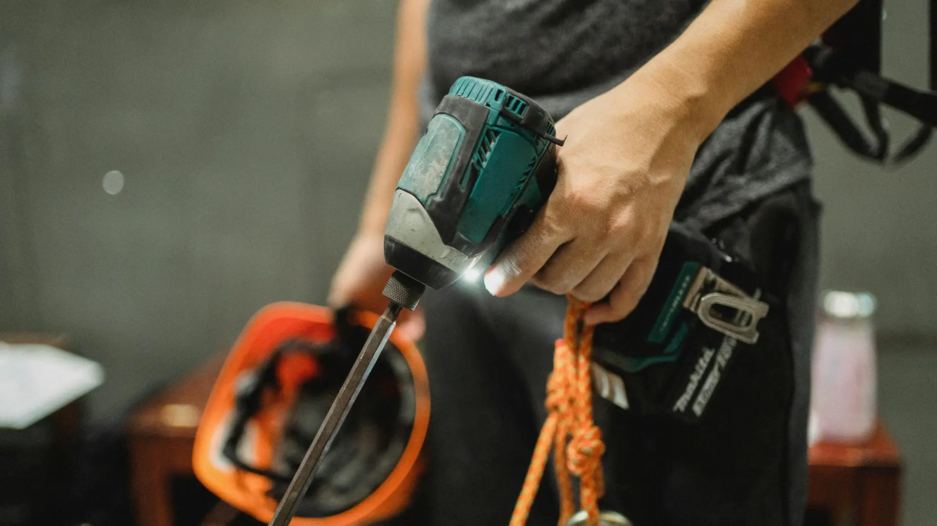A worker holding a power drill and helmet, ready for maintenance tasks.